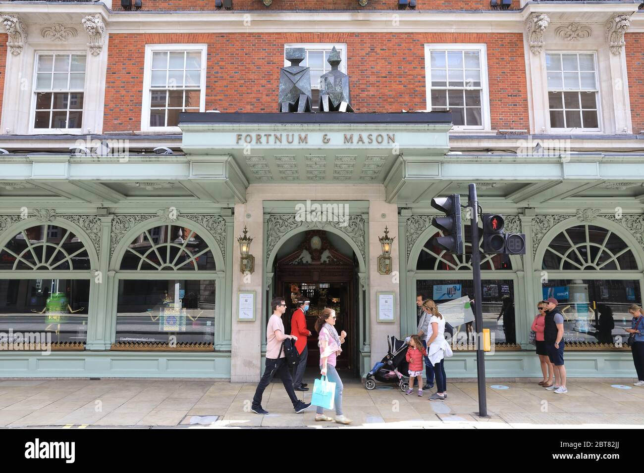 Fortnum & Mason Mitarbeiter mit Masken und Visieren begrüßen Kunden in seinem Flagship Store in Piccadilly, nachdem sie die Food Hall in London wiedereröffnet haben Stockfoto