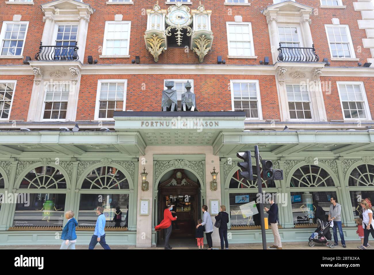 Fortnum & Mason Mitarbeiter mit Masken und Visieren begrüßen Kunden in seinem Flagship Store in Piccadilly, nachdem sie die Food Hall in London wiedereröffnet haben Stockfoto