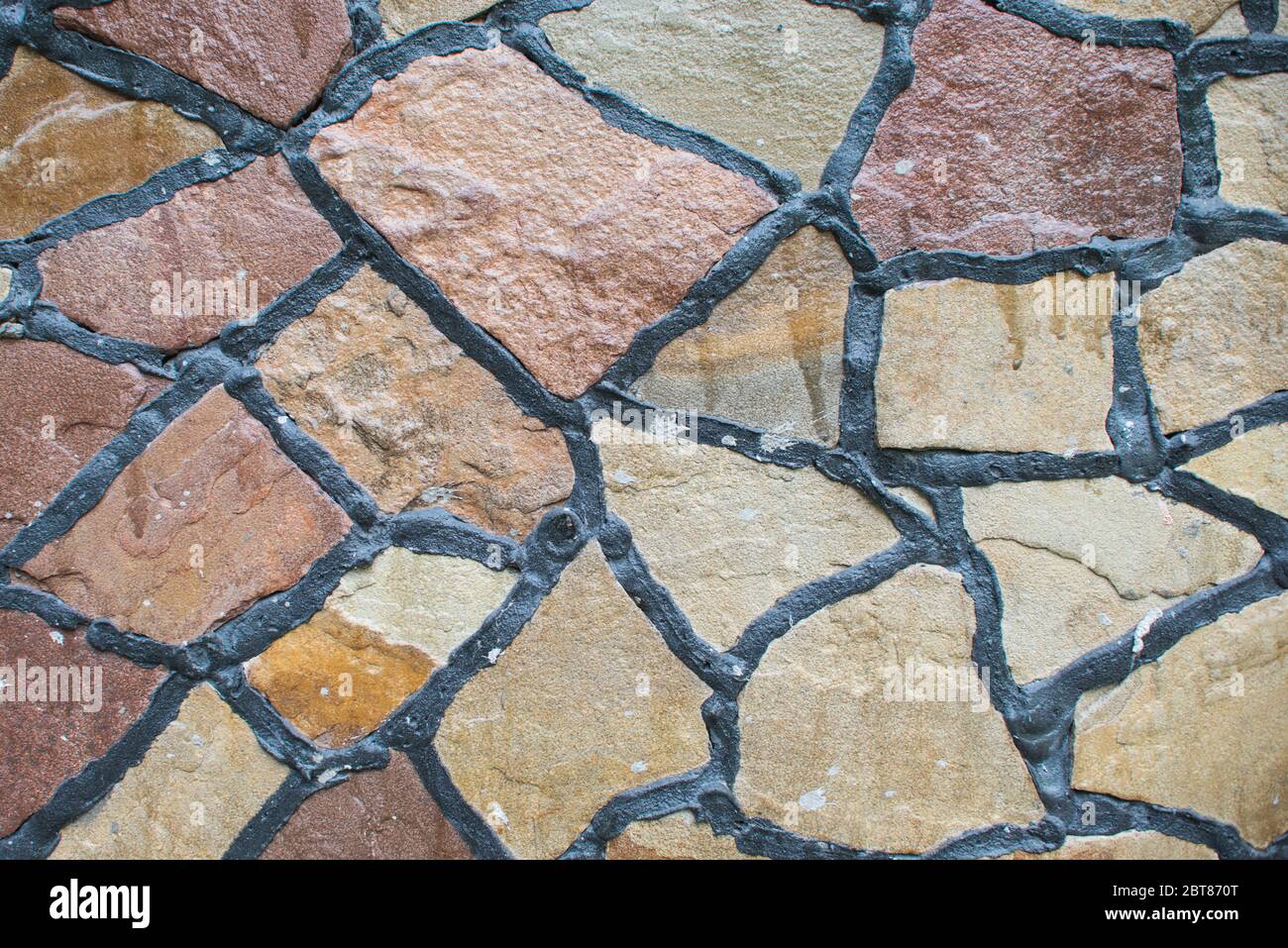 Natürliche farbige Stein Block Pflasterung Textur. Steinwand mit schwarzen Nähten. Hintergrund wird gebaut Stockfoto