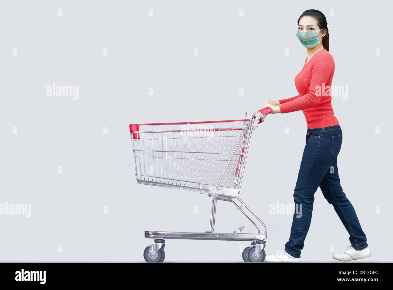 asiatische Frau Einkaufen im Kaufhaus mit Warenkorb mit Maske zu schützen Coronavirus Pandemie Stockfoto