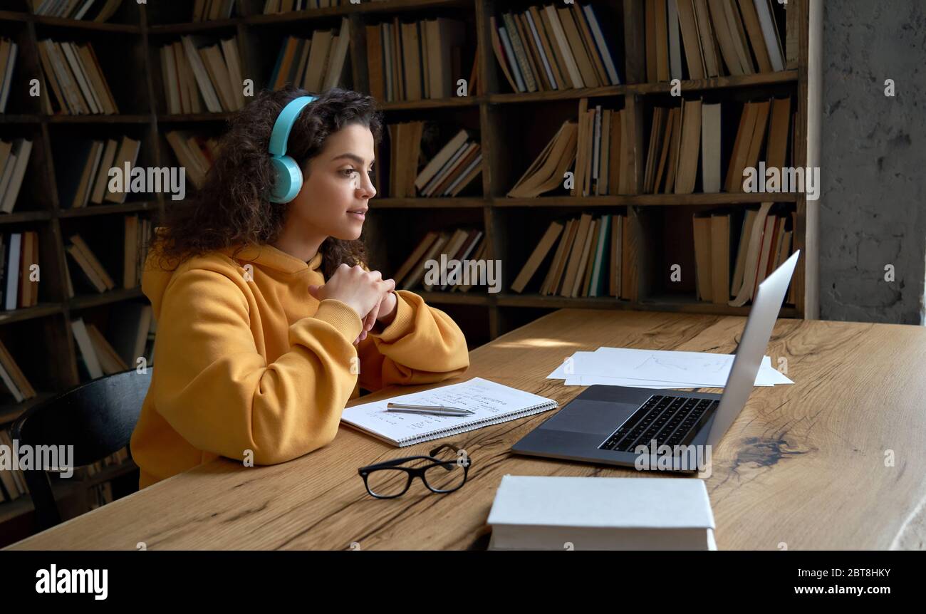 Hispanische Teenager Mädchen Student tragen Kopfhörer Online-Webinar auf Laptop ansehen. Stockfoto