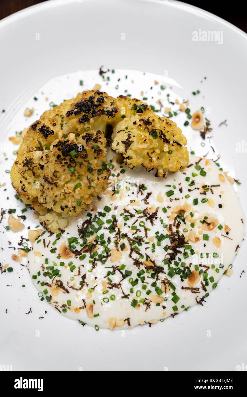 Geröstete Blumenkohl mit Parmesan und Haselnuss Belag mit Frühlingszwiebeln und Blumenkohlensuppe, Gourmet-Rezept der internationalen Küche. Restaurant Gastro Stockfoto