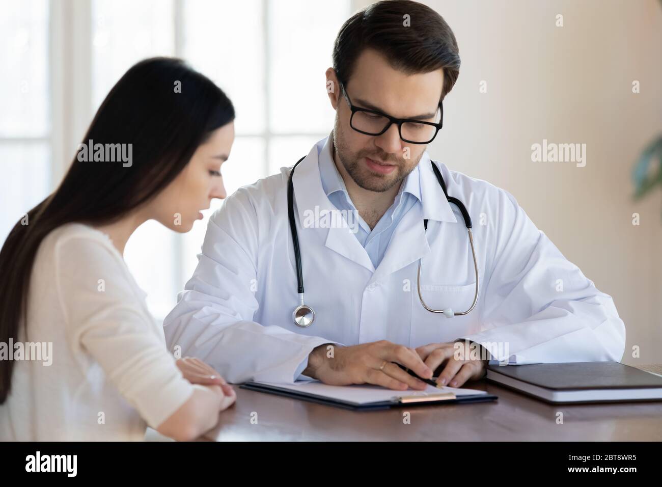 Männlicher Arzt erklären Rezept für weibliche Patienten bei der Konsultation Stockfoto