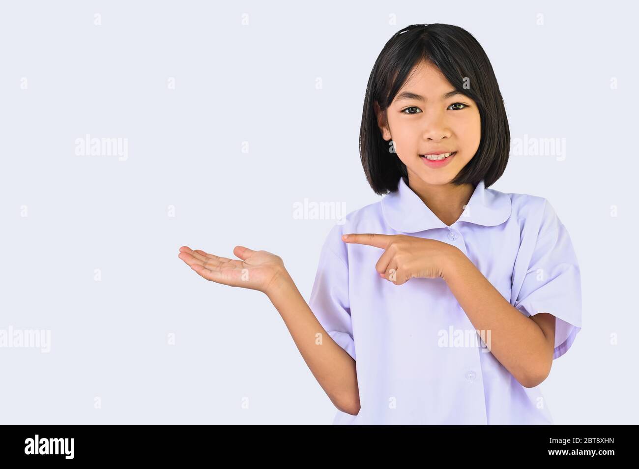 Asiatische kleine Schulmädchen zeigt etwas über ihre Hand und Finger zeigen, Kind suchen Lächeln auf Kamera in weißem Hintergrund für die Show oder isoliert Stockfoto