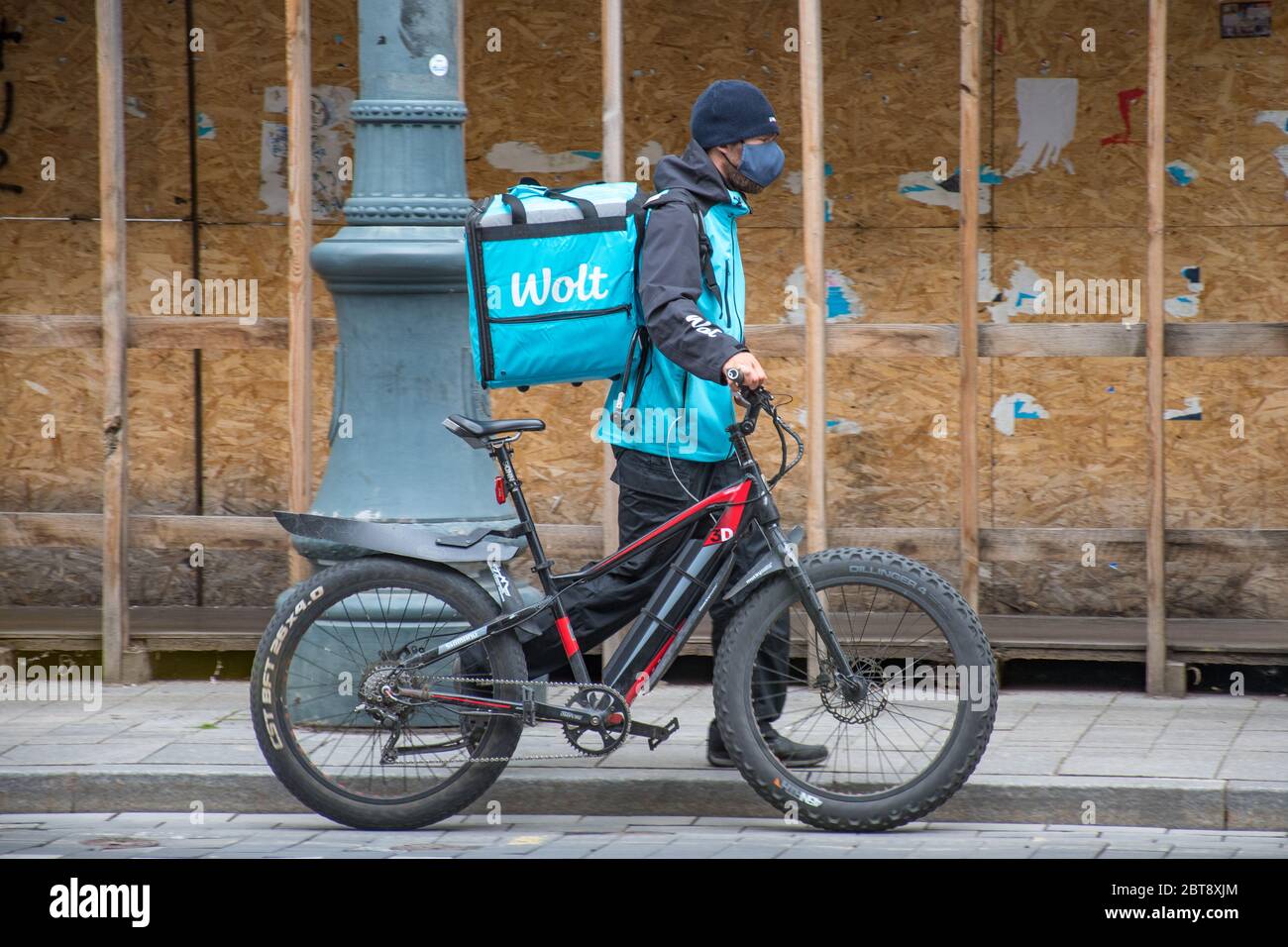 Wolt, Online-Food-Bestell-und Lieferservice, die Bestellungen über eine mobile App nimmt, Fahrer mit Fahrrad und Maske Stockfoto