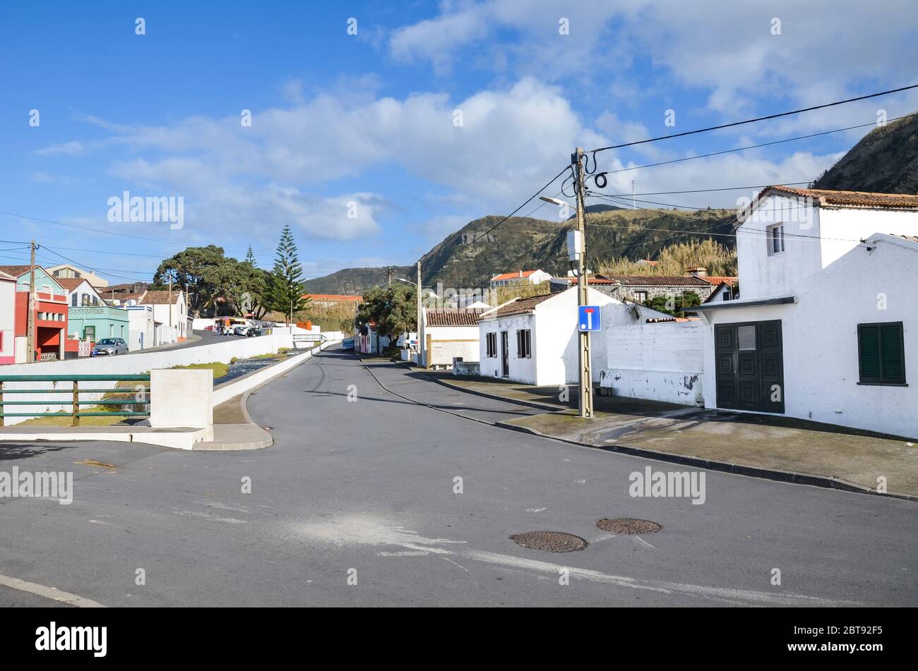 Mosteiros, Azoren, Portugal - 12. Jan 2020: Blick auf das traditionelle portugiesische Dorf auf den Azoren. Häuser mit weißen Fassaden, Asphaltstraße, Stromleitung. Horizontales Foto. Stockfoto