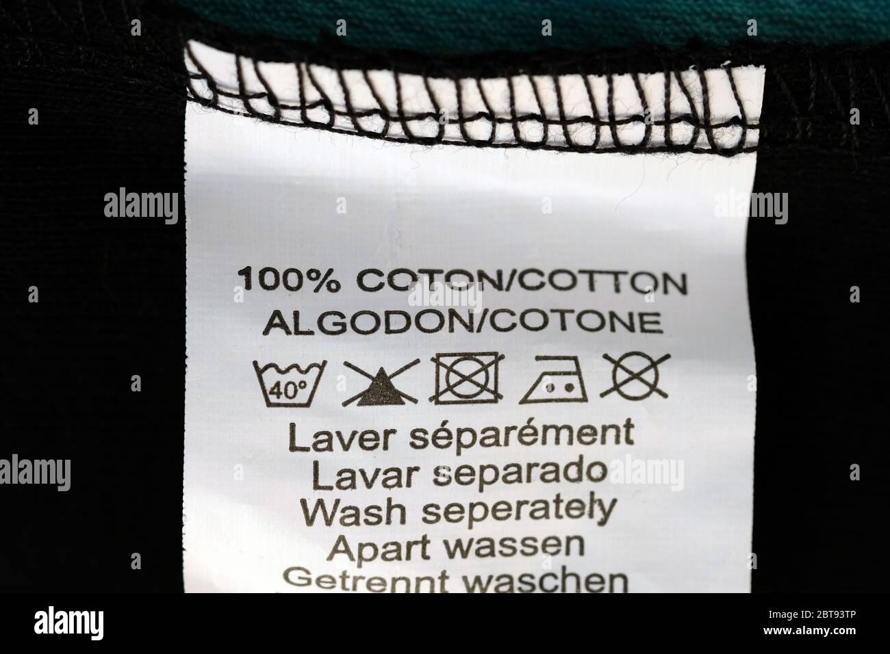 Etikett mit Waschanleitung. Weißes Etikett mit Anweisungen für die Zusammensetzung des Stoffes 100% Baumwolle und Symbole, welche Temperatur zu waschen und ir Stockfoto