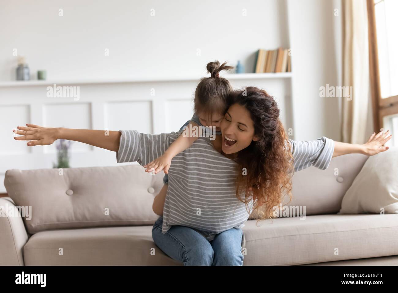 Lachende Mutter huckepack kleine Tochter, lustiges Spiel spielen Stockfoto