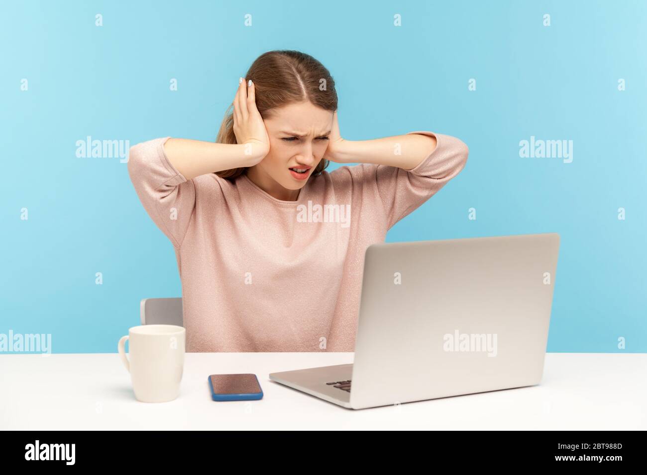 Ich möchte Sie nicht hören. Wütende Frau Angestellte Ohren bedeckt und sieht irritierend auf Laptop-Bildschirm, ärgerlich durch unangenehme Kommunikation auf Video-Anruf. Stockfoto