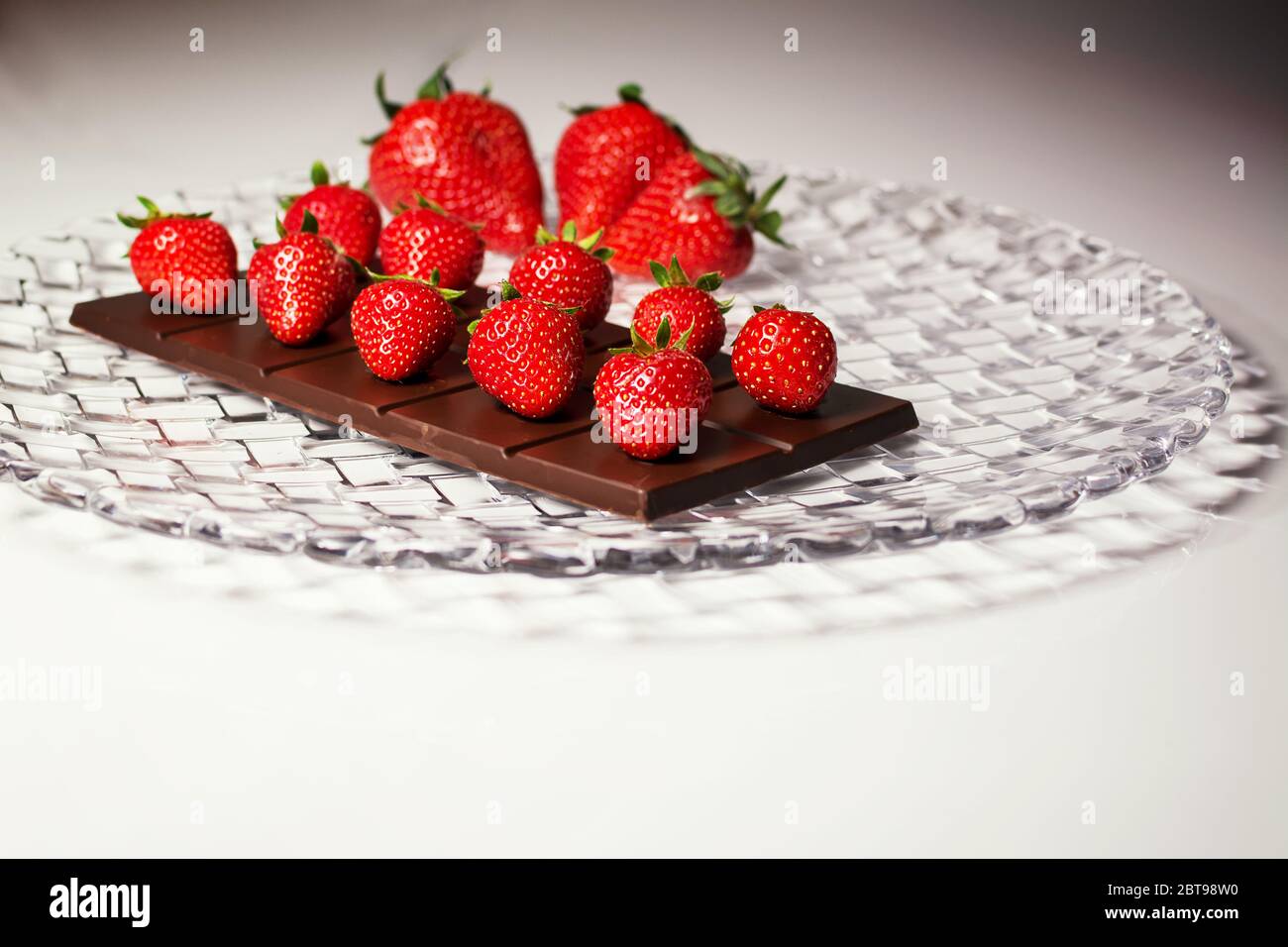 Eine Gericht Zusammensetzung mit Choccolate Tablette und Erdbeeren auf und große Erdbeeren verschwommen im Hintergrund Stockfoto