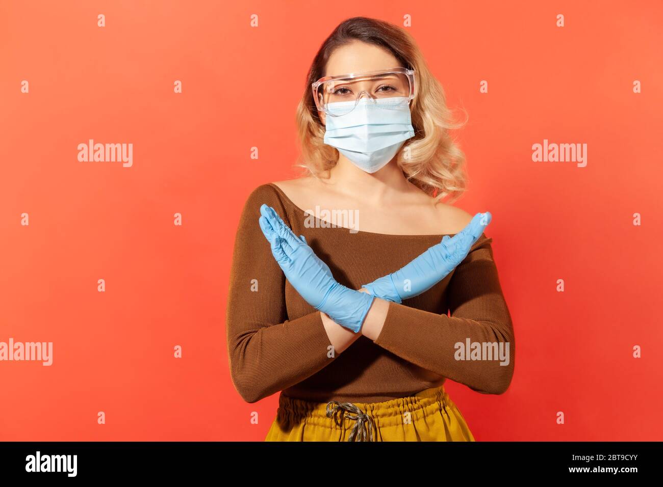 Mehr nicht! Frau trägt hygienische Gesichtsmaske, Handschuhe und Schutzbrille, zeigt Stopp, x Zeichen, Ablehnung 2019-ncov Coronavirus Pandemie Bedrohung. ich Stockfoto