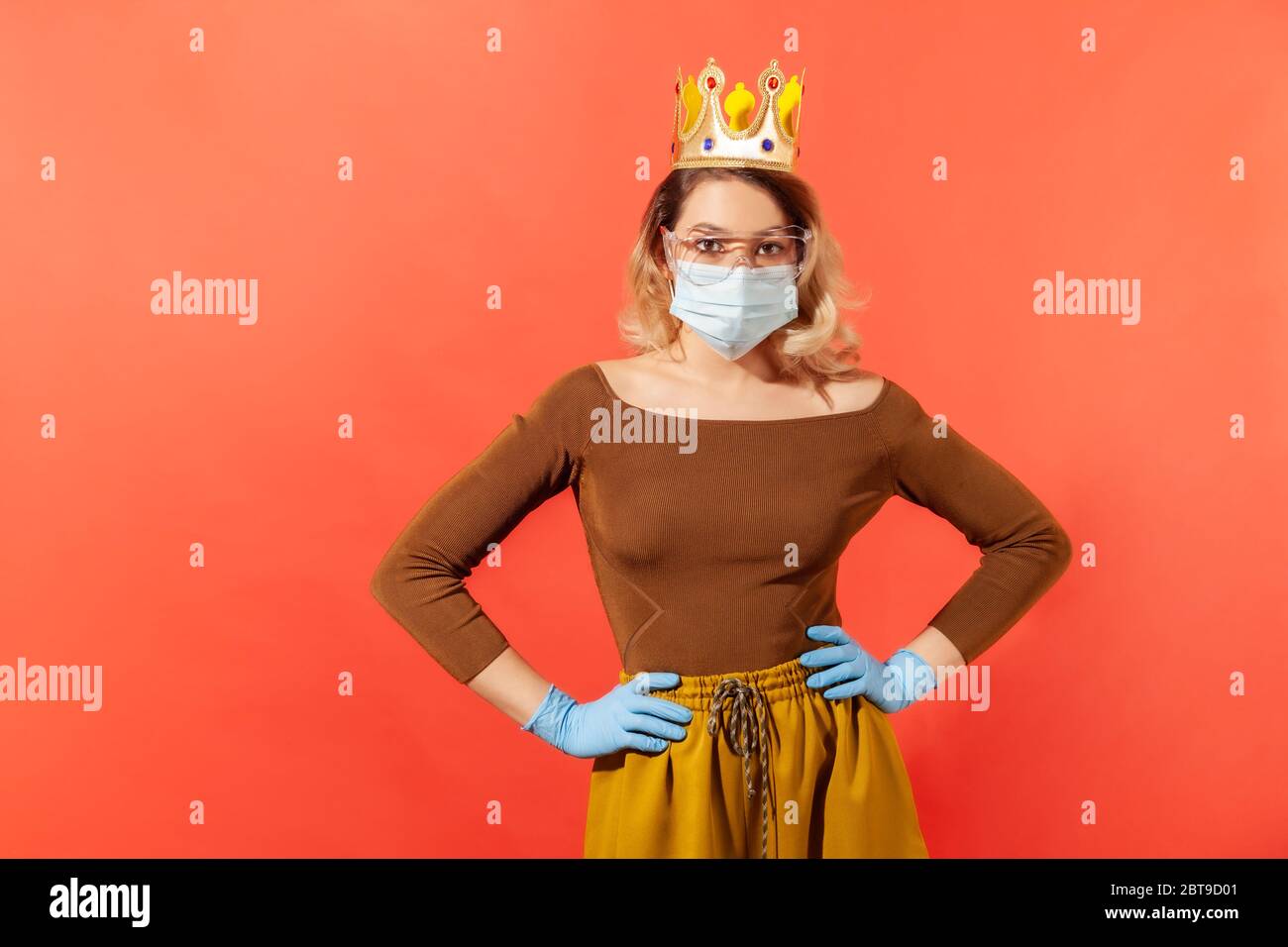 Frau mit goldener Krone auf dem Kopf, trägt hygienische Maske, Brille und Schutzhandschuhe gegen ansteckende Grippe Coronavirus, 2019-ncov-Krankheit zu schützen, lo Stockfoto