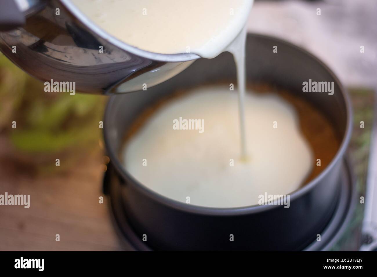 Einen New Yorker Käsekuchen oder klassischen Käsekuchen machen: Die Käsecreme auf der Plätzchenbasis hinzufügen Stockfoto