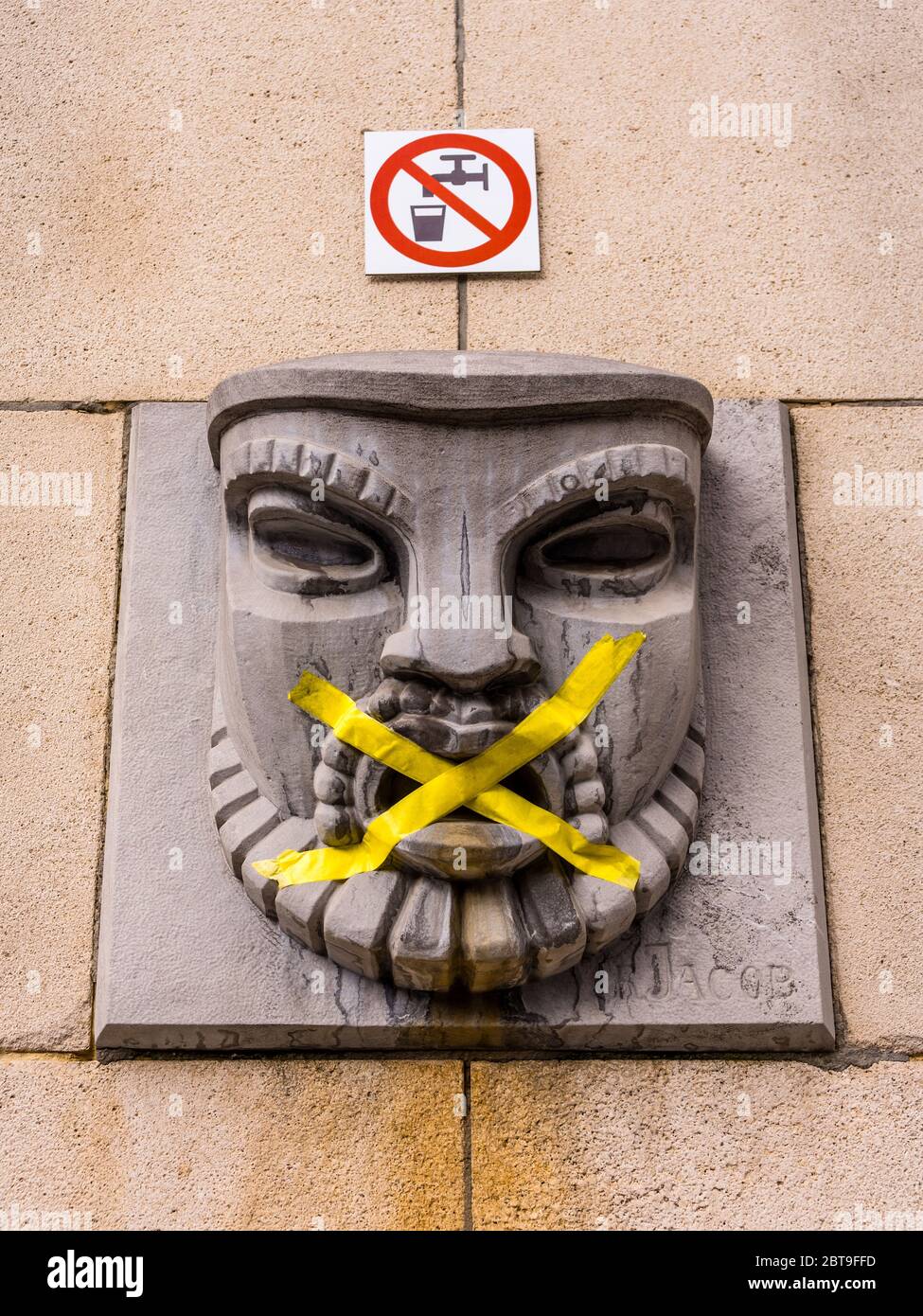 Mit Klebeband blockierter Brunnen mit geschnitztem Kopf, Rue du Musée, Brüssel, Belgien. Stockfoto
