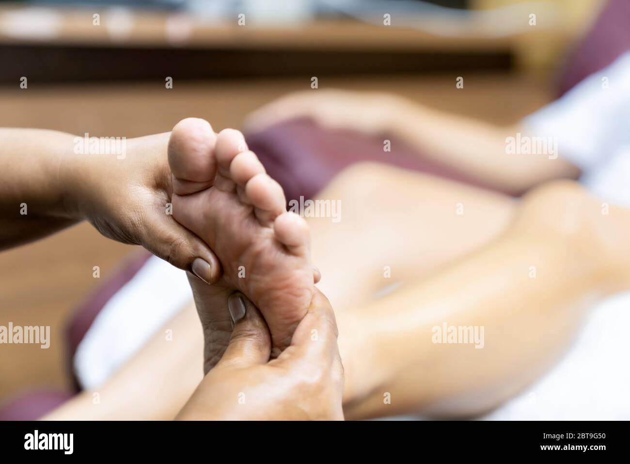Quarantäne asiatische Frau tun Fußmassage zu Hause, während Stadt gesperrt für soziale Distanz aufgrund von Coronavirus Pandemie. Massage und Spa ist eine der Service Stockfoto