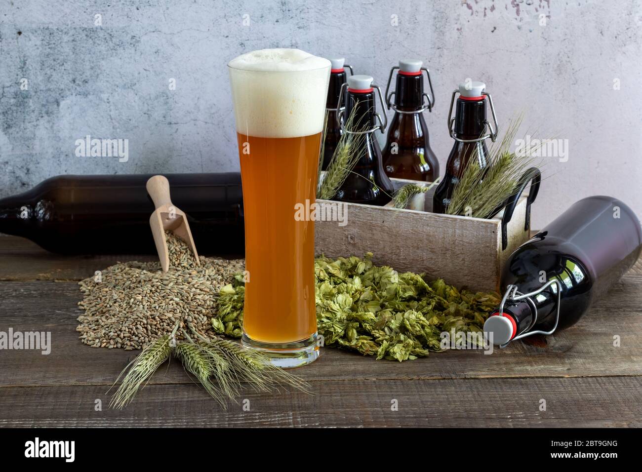 Weizenbier in Hochglas mit Weizen, Hopfen und Flaschen. Stockfoto