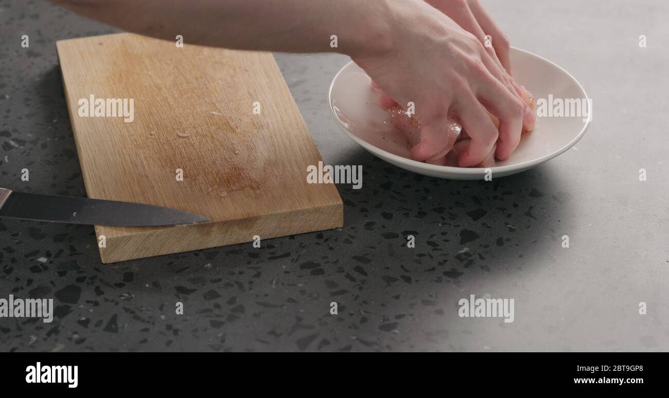 Man Hand marinieren Hühnerscheiben in weißer Schüssel mit Gewürzen Stockfoto