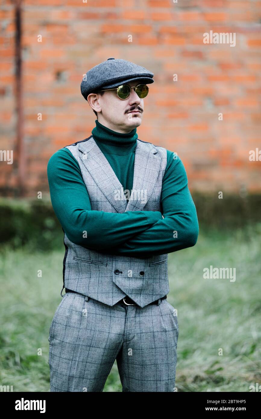 Gut gekleideter Mann mit grauem Retro-Anzug, Mütze und grünem Jersey  Stockfotografie - Alamy