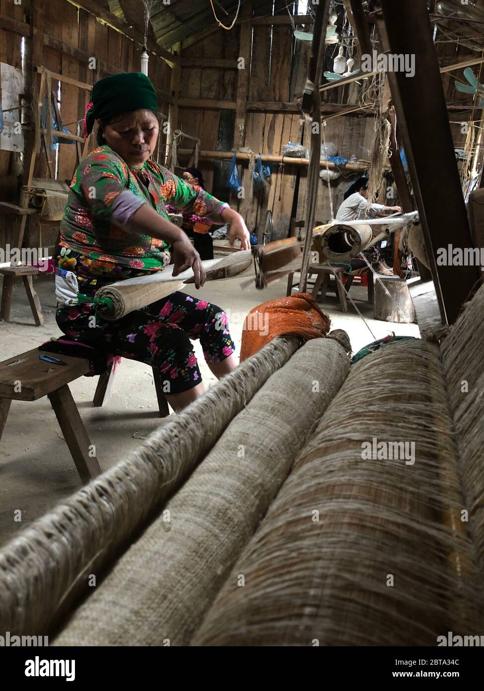 Lung Tam, Vietnam - 9. Januar 2020 - Frau, die auf traditionelle Weise webt, konzentriert sich auf lin und Webstuhl Stockfoto