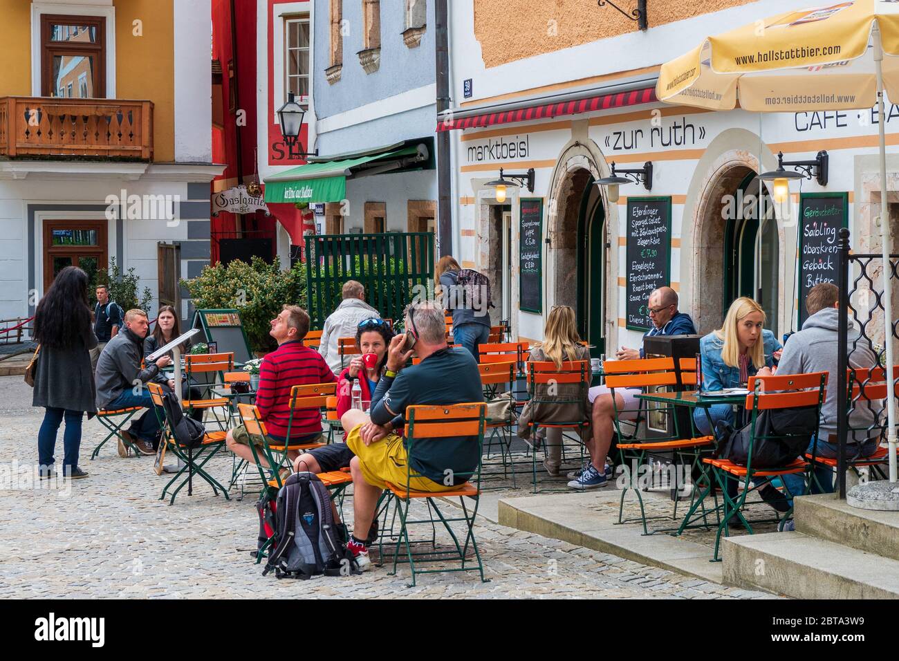 Blick auf die Menschen in einem Bürgersteig-Café auf dem Marktplatz von Hallstatt, Salzkammergut, OÖ, Österreich Stockfoto