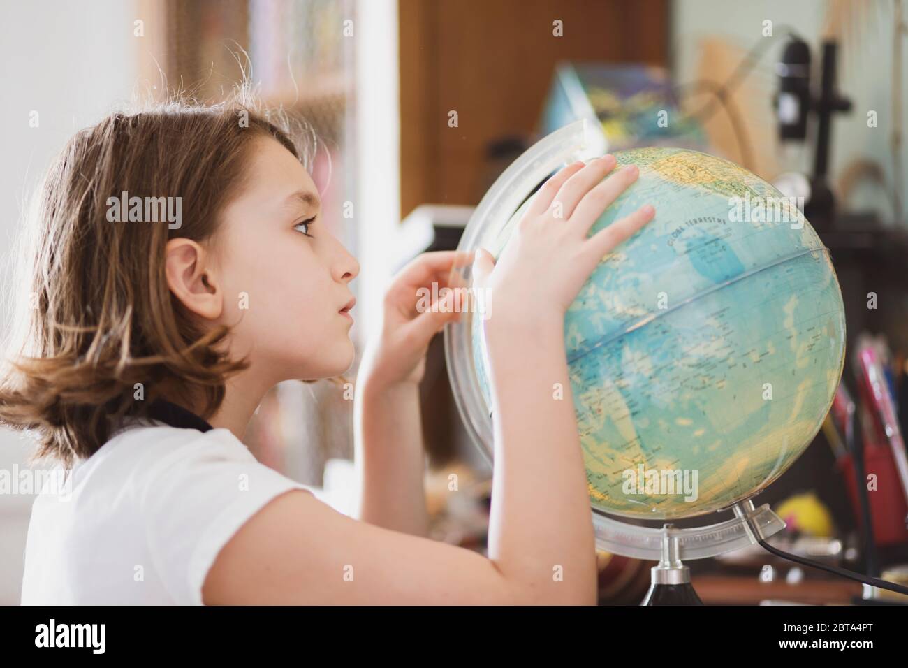 Junges Mädchen siiting an ihrem Schreibtisch und beobachten einen Globus.. Stockfoto