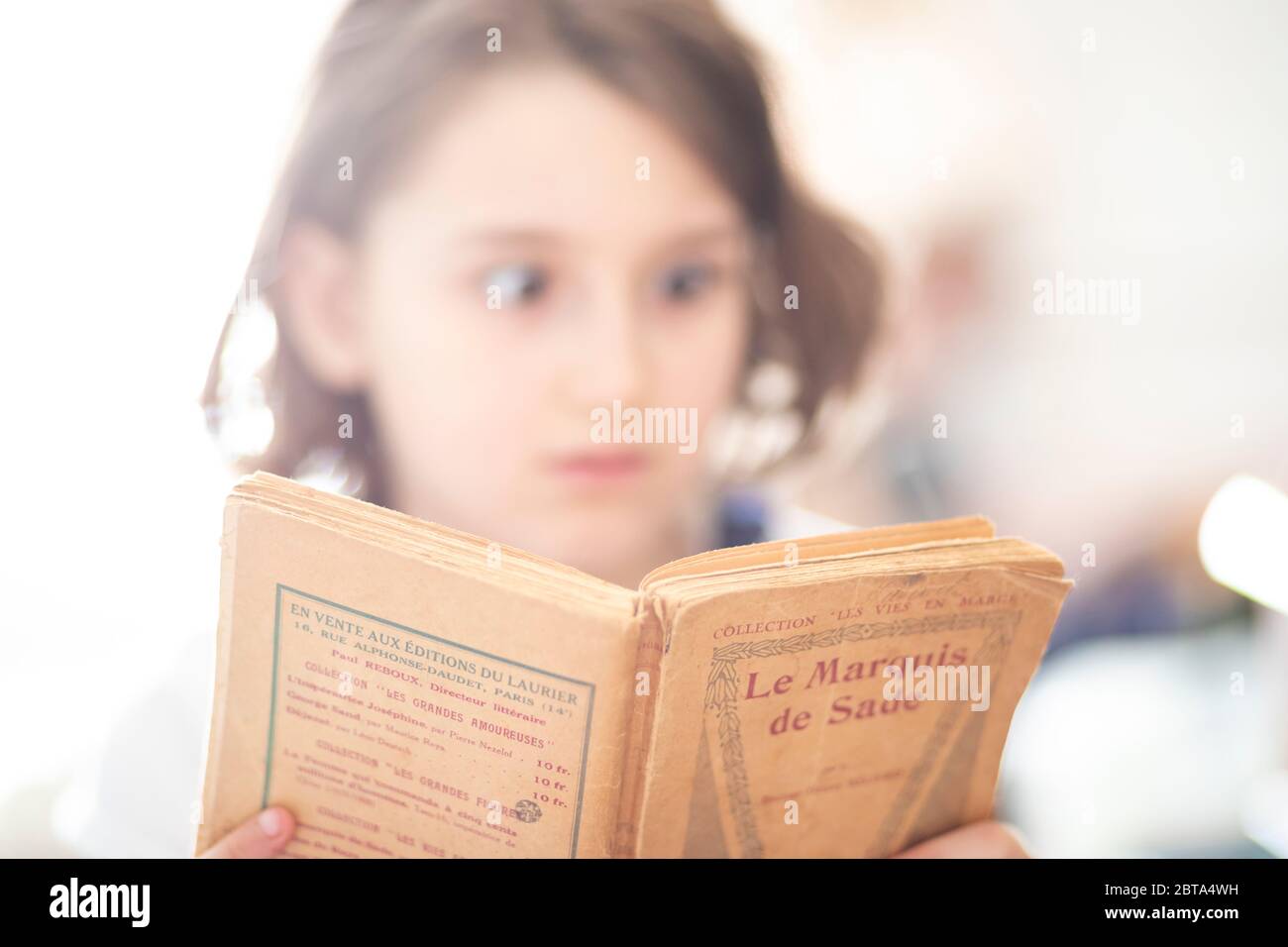 Schockierte junge Mädchen, während ein Buch über Le Marquis de Sade lesen Stockfoto