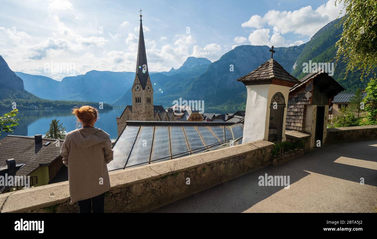 Weibliche Touristen betrachten die atemberaubende Hallstatt, Salzkammergut Region, OÖ, Österreich, von einem erhöhten Aussichtspunkt über den Dächern des berühmten Dorfes Stockfoto