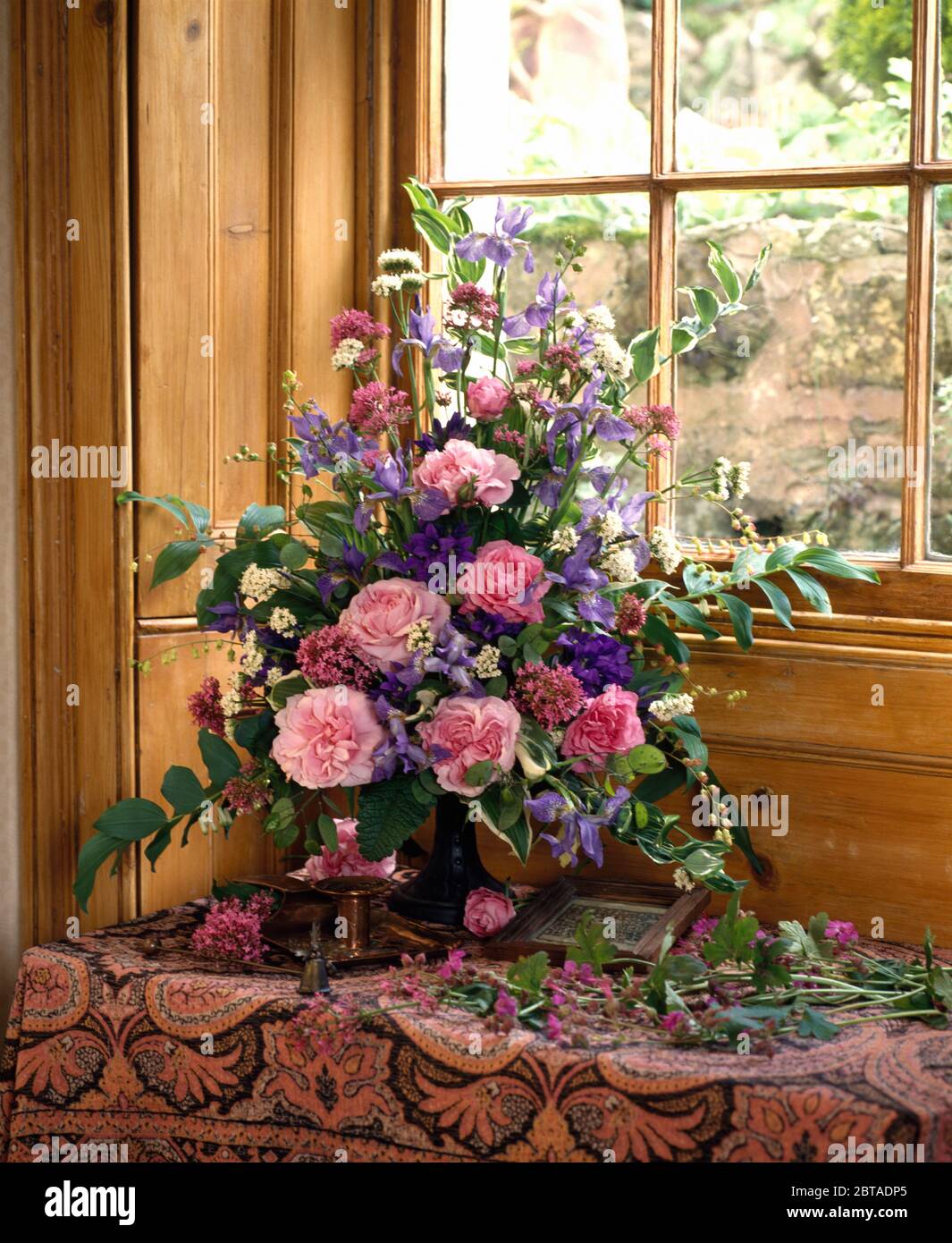 Nahaufnahme von rosa Rosen und blauen Iris in einem informellen Blumenarrangement Stockfoto