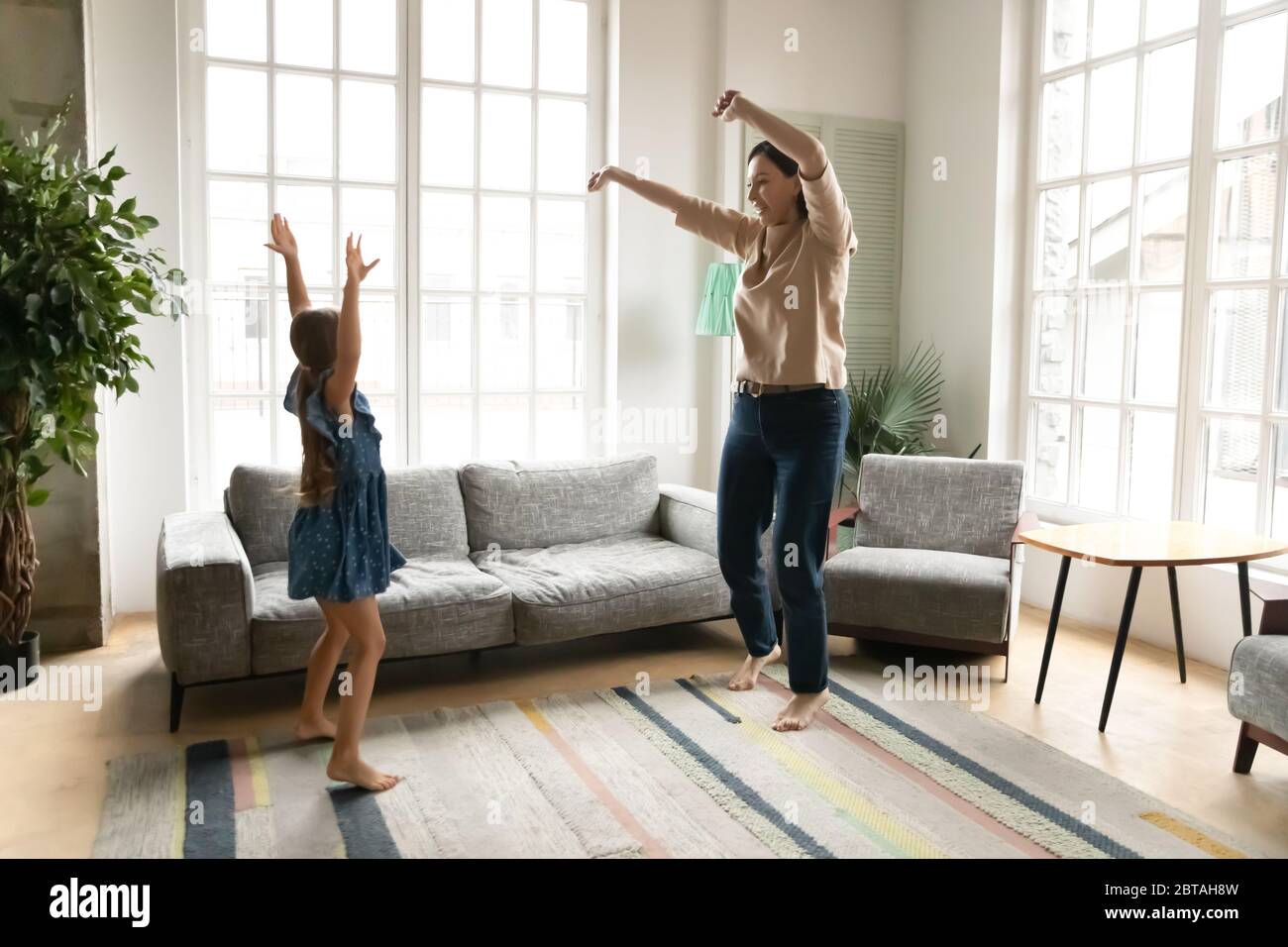 Energetische Großmutter tanzt im Wohnzimmer mit Enkelin Stockfoto
