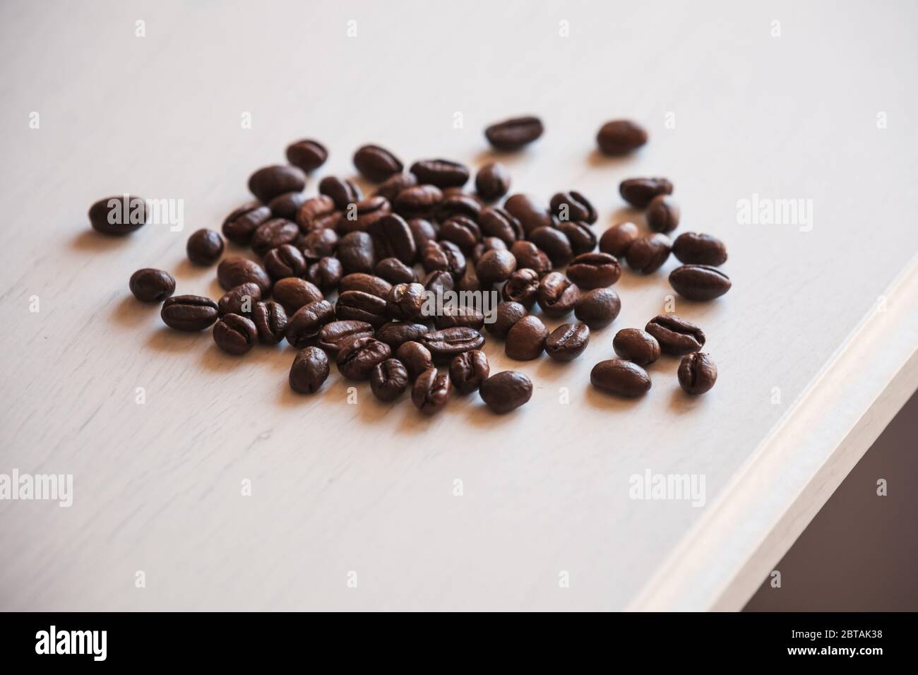 Geröstete Kaffeebohnen sind auf weißem Holztisch, Nahaufnahme Foto mit selektiver Weichstellung Stockfoto