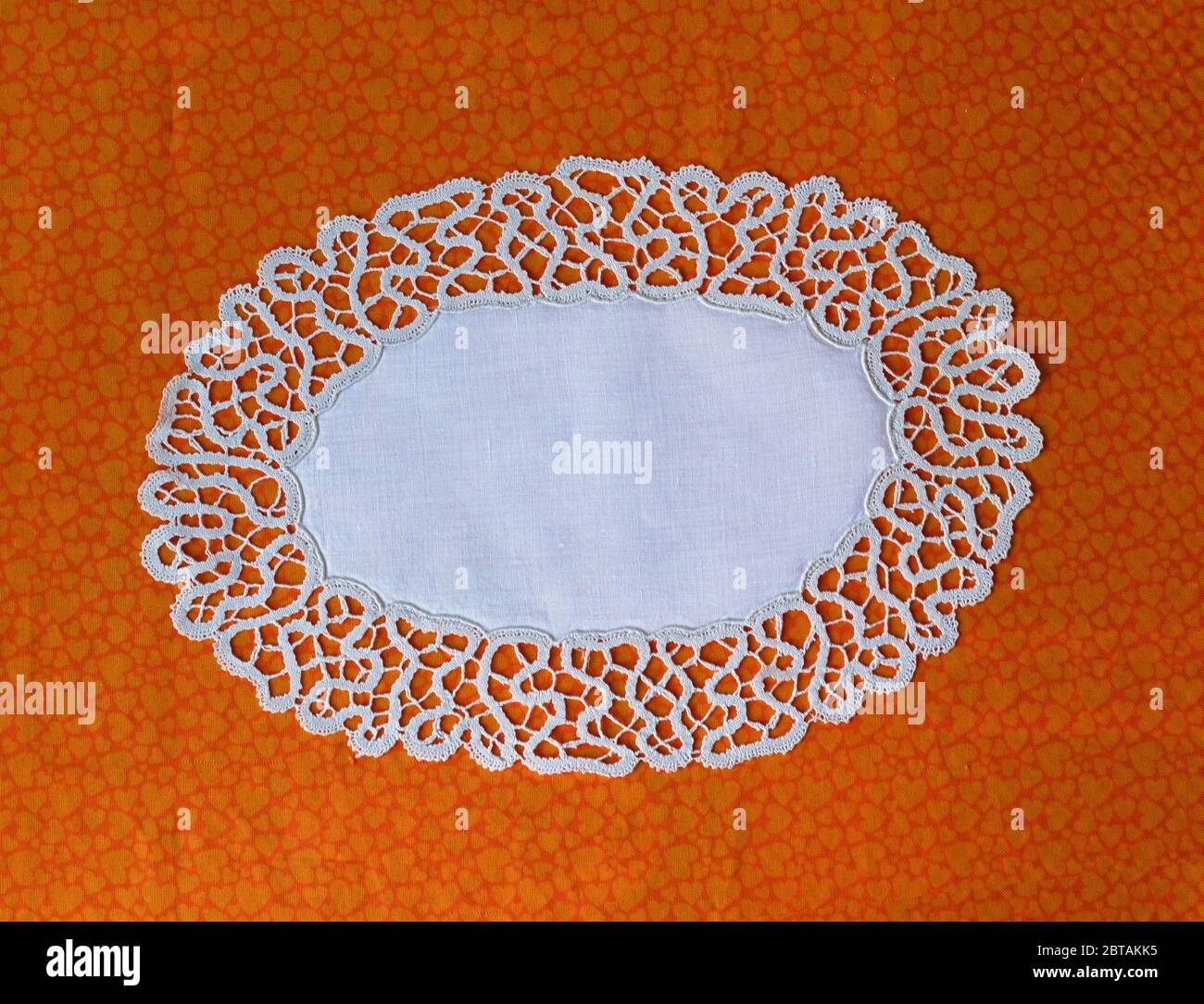 Antikes handgefertigtes Spitzenherz auf orangefarbenem Hintergrund Stockfoto