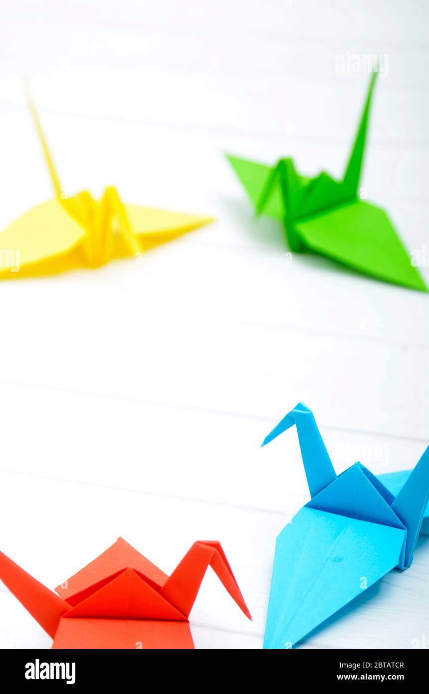 Origami, Kunst mit Papier zu schaffen, einen Vogel, mit Farbpapier, rot, blau, grün und gelb. Kreativität. Foto mit weißem Hintergrund Stockfoto