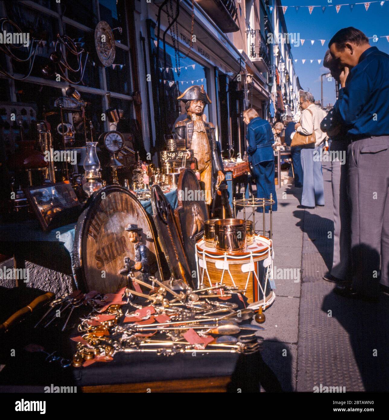 Touristen, Händler und Sammler stöbern in den 1970er Jahren in der Portobello Road im Londoner Nottiing Hill in den Antiquitäten und Kuriosen der Tischkiste Stockfoto