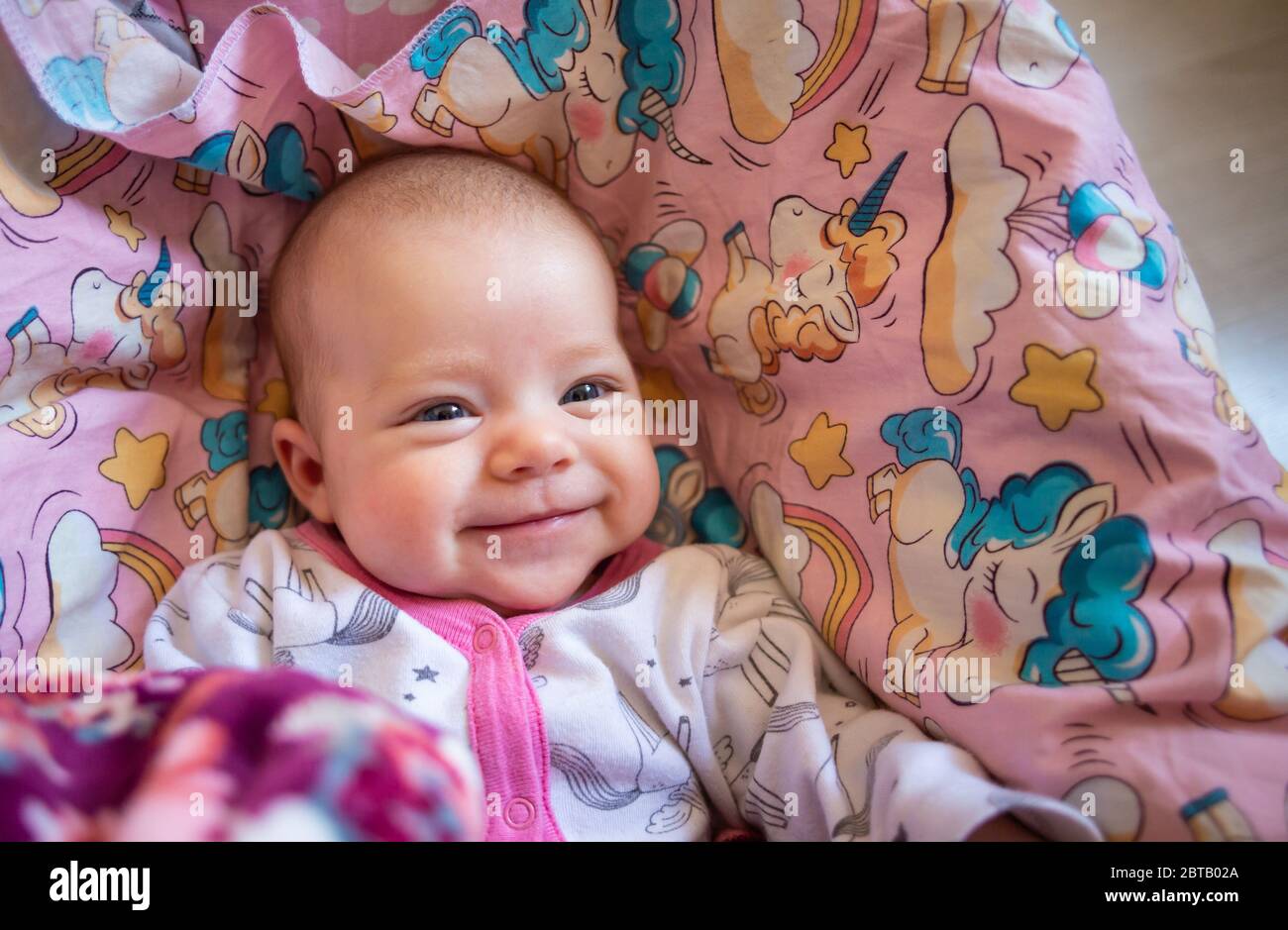 Ziemlich lächelndes Baby Mädchen und Spielzeug Kaninchen liegen in hellen Hintergrund Stockfoto