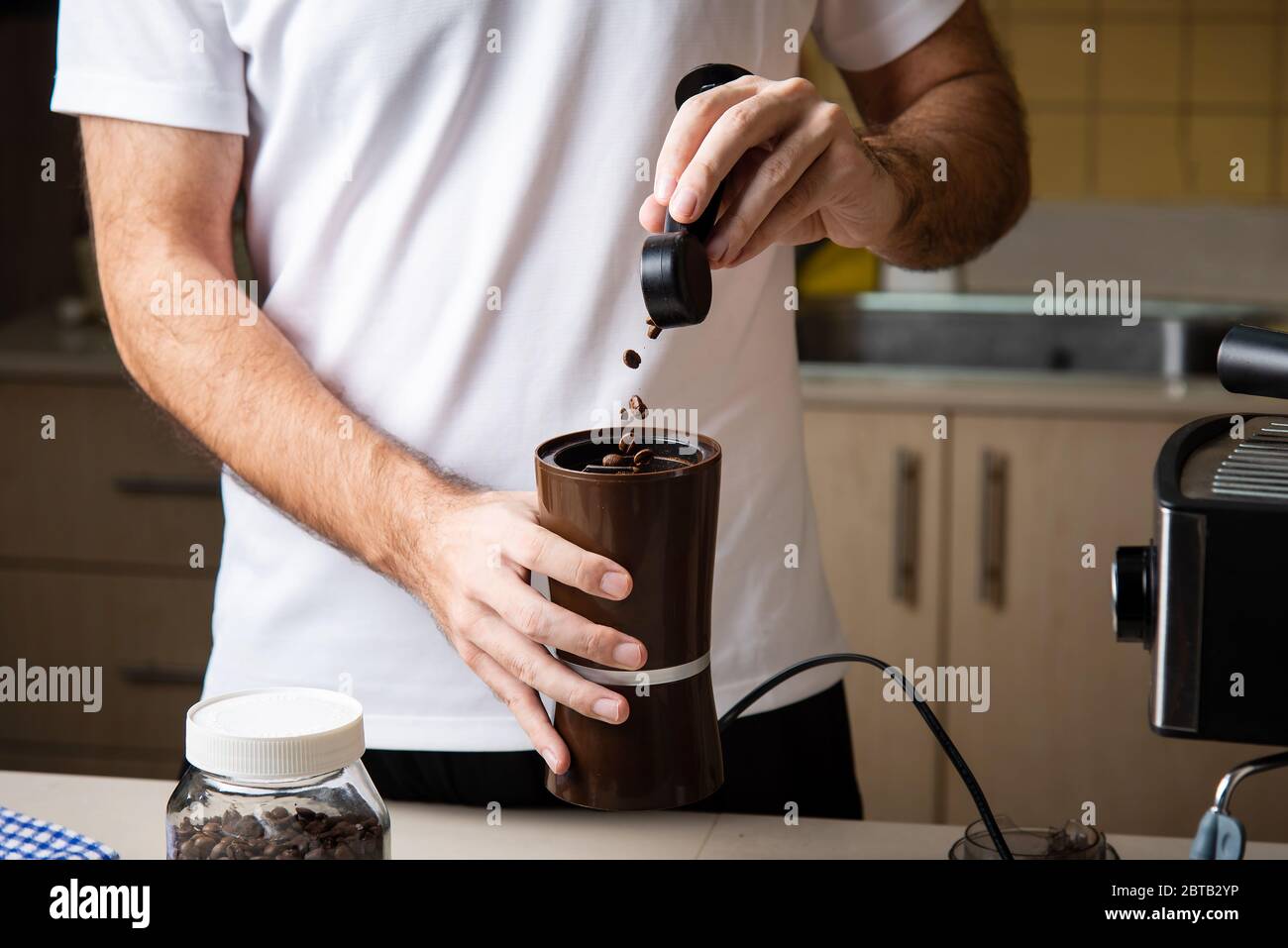 Mann, der Kaffeebohnen für die Zubereitung eines Espresso mahlen kann. Lifestyle-Konzept für den Barista im Haus Stockfoto