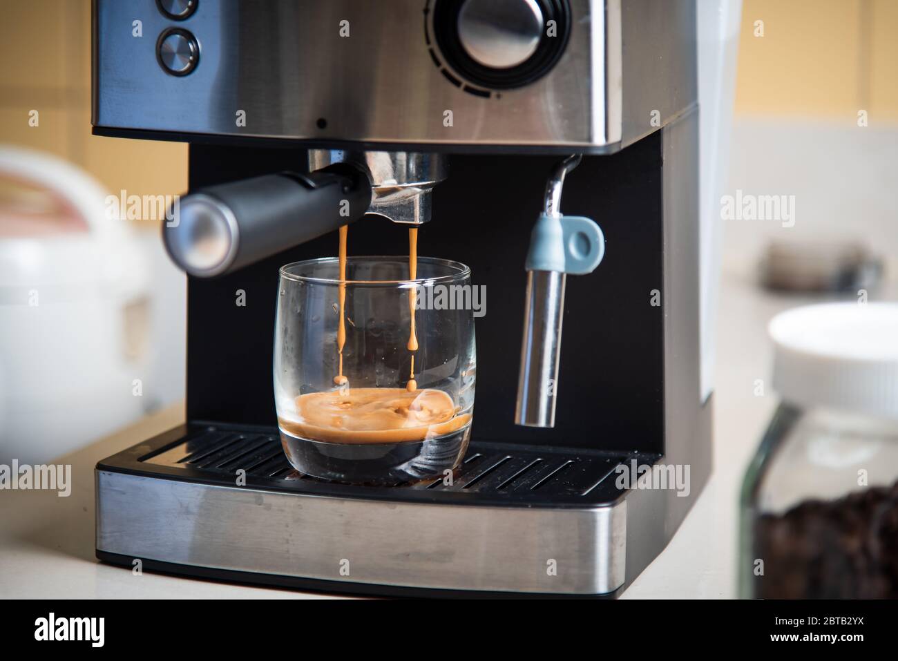 Espresso aus einer Kaffeemaschine in einem Glasaufbereitungsgerät zubereiten Stockfoto