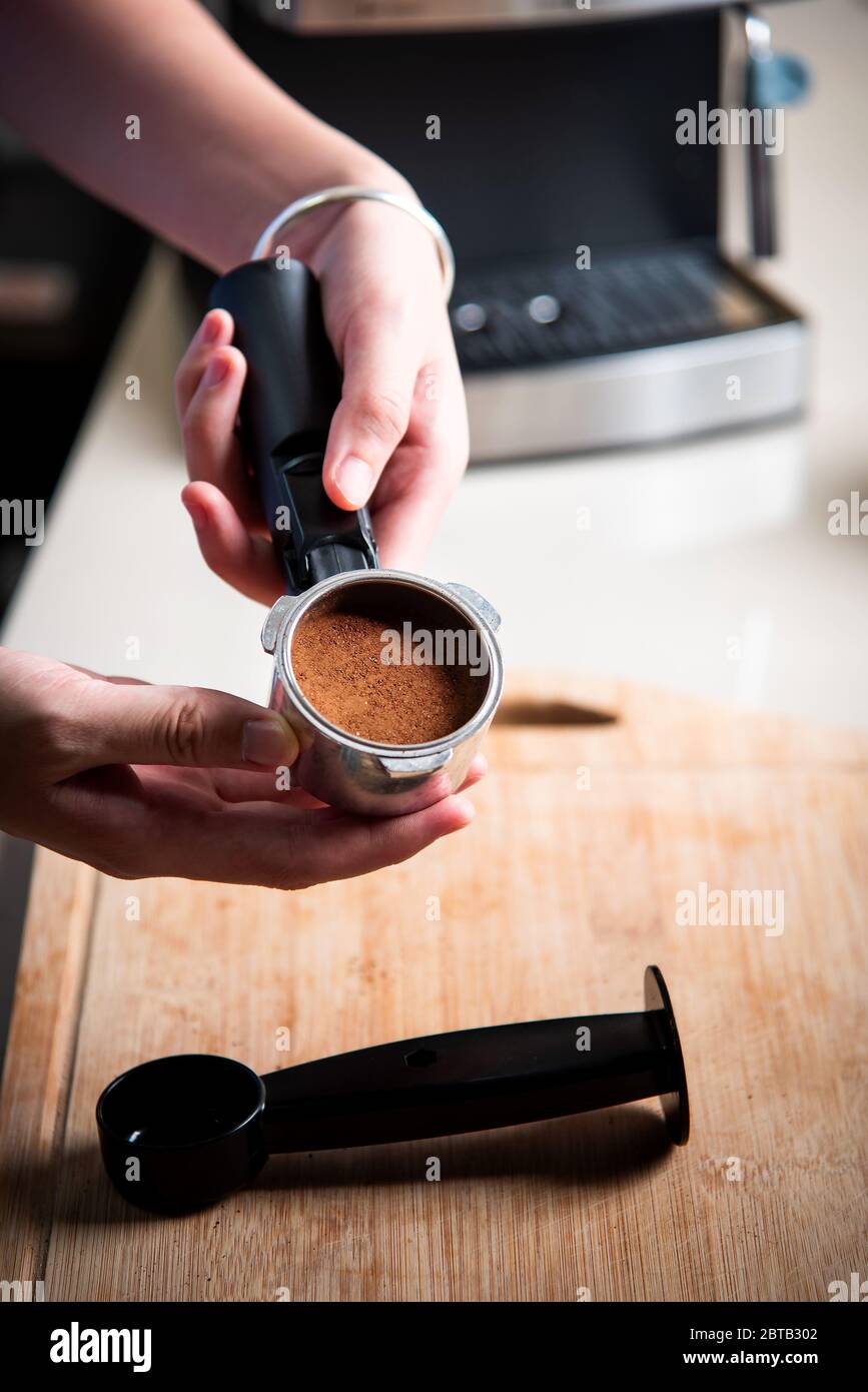 Frau arrangiert Kaffee gemahlenes Pulver in portafilter Korb. Lifestyle-Konzept für den Barista im Haus Stockfoto