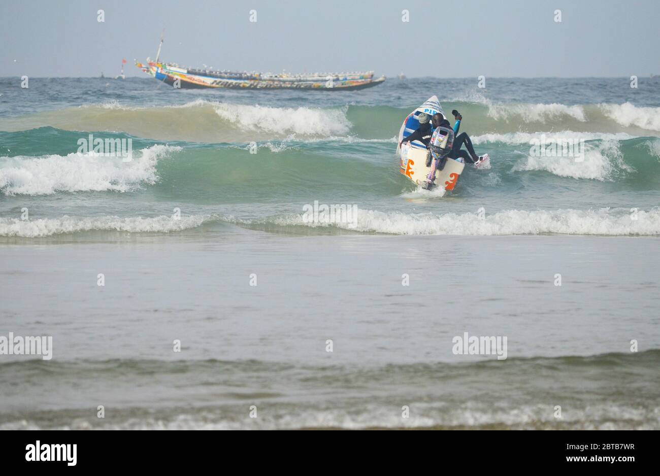 Ein Pirogue (handwerkliches Fischerboot), das sich am Yoff Beach, Dakar, Senegal, der Brandung trotzt Stockfoto