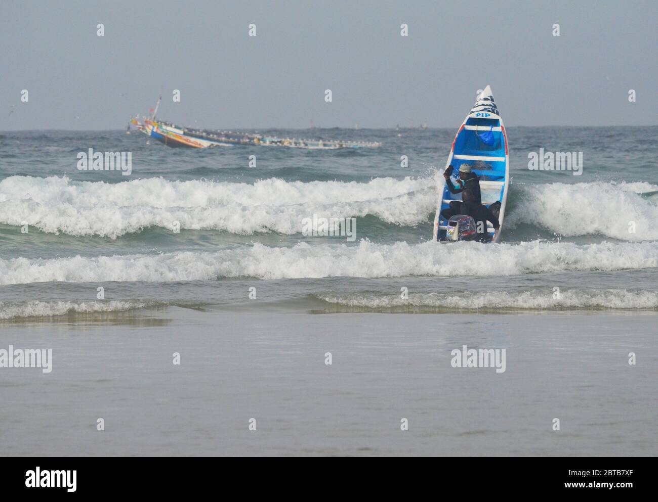 Ein Pirogue (handwerkliches Fischerboot), das sich am Yoff Beach, Dakar, Senegal, der Brandung trotzt Stockfoto