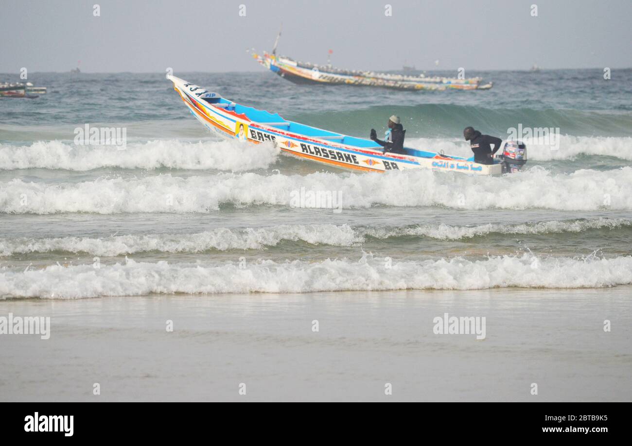 Ein Pirogue (handwerkliches Fischerboot), das sich am Yoff Beach, Dakar, Senegal, der Brandung trotzt Stockfoto