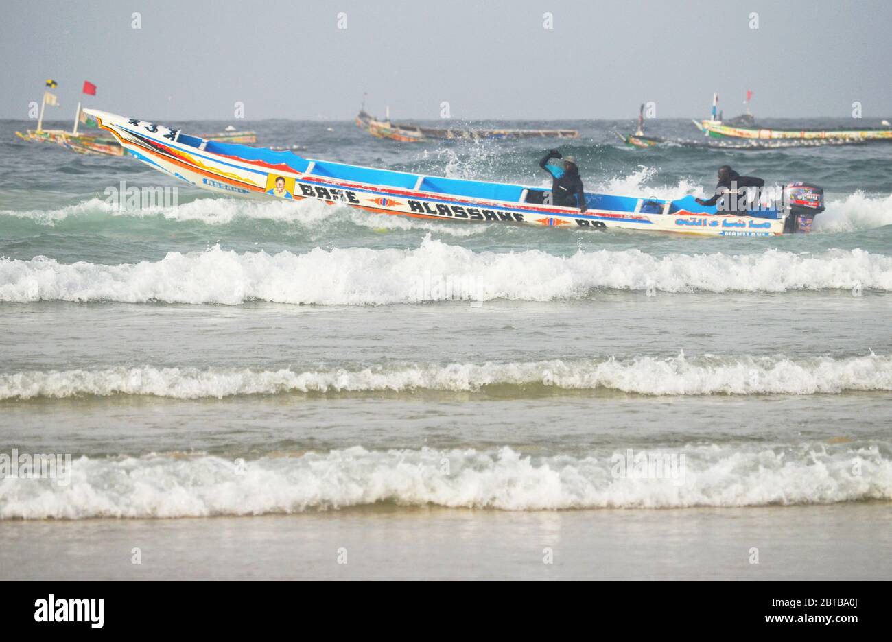 Ein Pirogue (handwerkliches Fischerboot), das sich am Yoff Beach, Dakar, Senegal, der Brandung trotzt Stockfoto