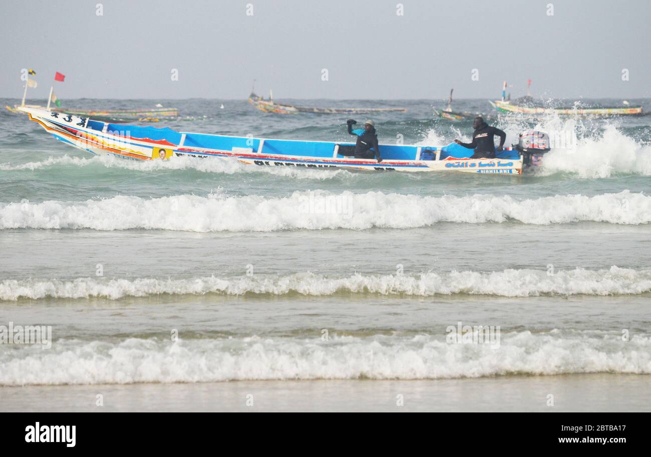 Ein Pirogue (handwerkliches Fischerboot), das sich am Yoff Beach, Dakar, Senegal, der Brandung trotzt Stockfoto