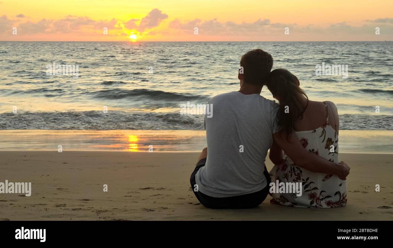 Ein schönes junges Paar umarmte sich am leeren Strand am Meer und beobachtete den Sonnenuntergang im tropischen Resort am Abend mit Blick auf den Rückseitenbereich Stockfoto