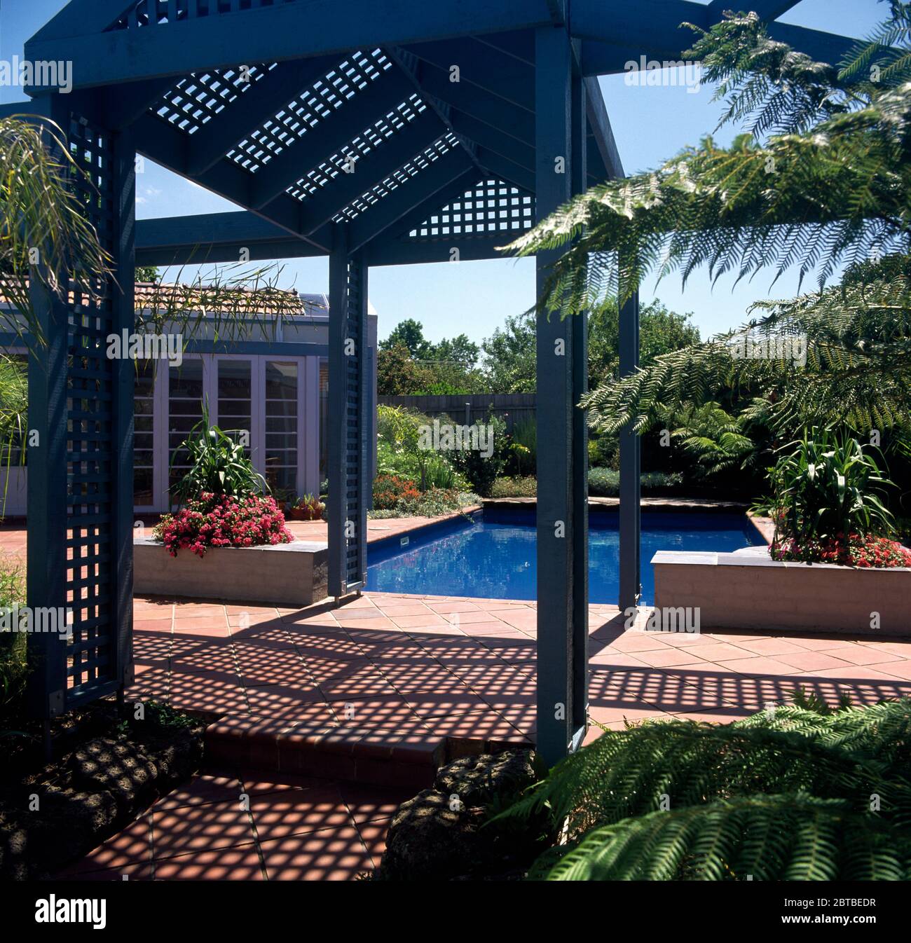Blick durch ein rankgitter Gazebo eines blauen Pool Stockfoto