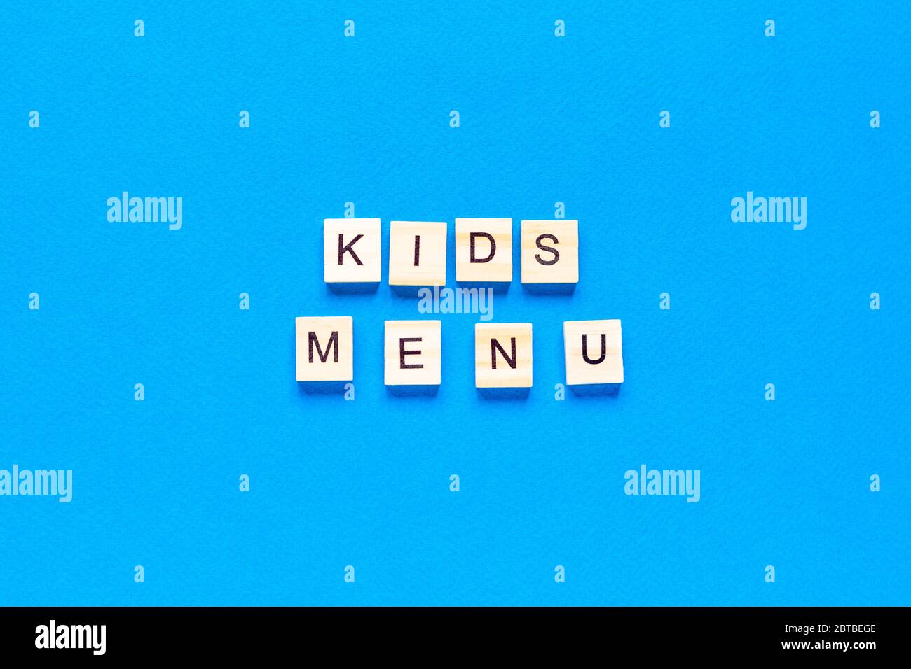 Kinder Menü Inschrift in Holzbuchstaben auf blauem Hintergrund, flaches Layout, Draufsicht, lassisch blaue Farbe Stockfoto