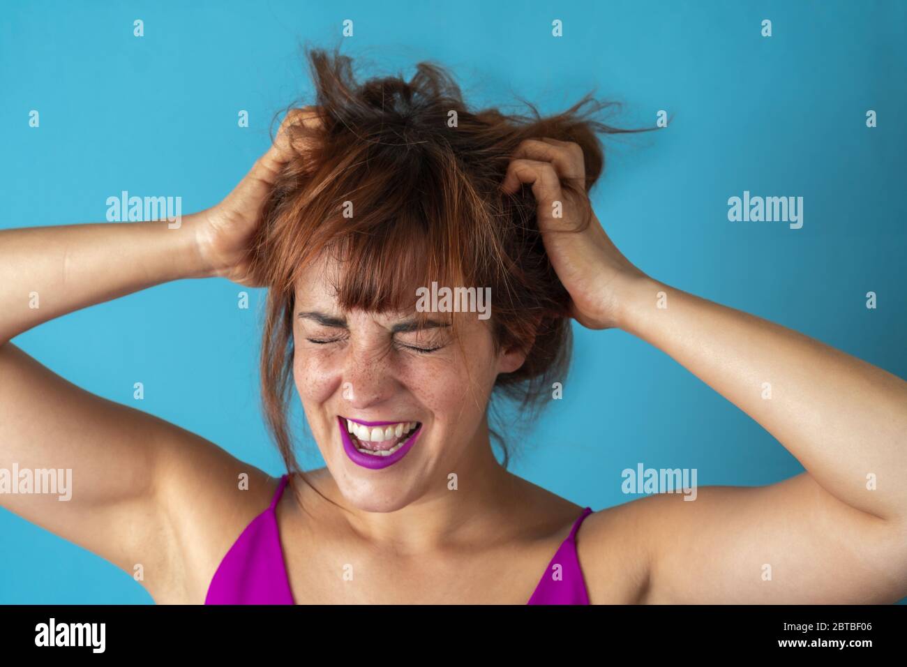 Gestresste junge Frau, die beim Schreien an den Haaren zieht Stockfoto