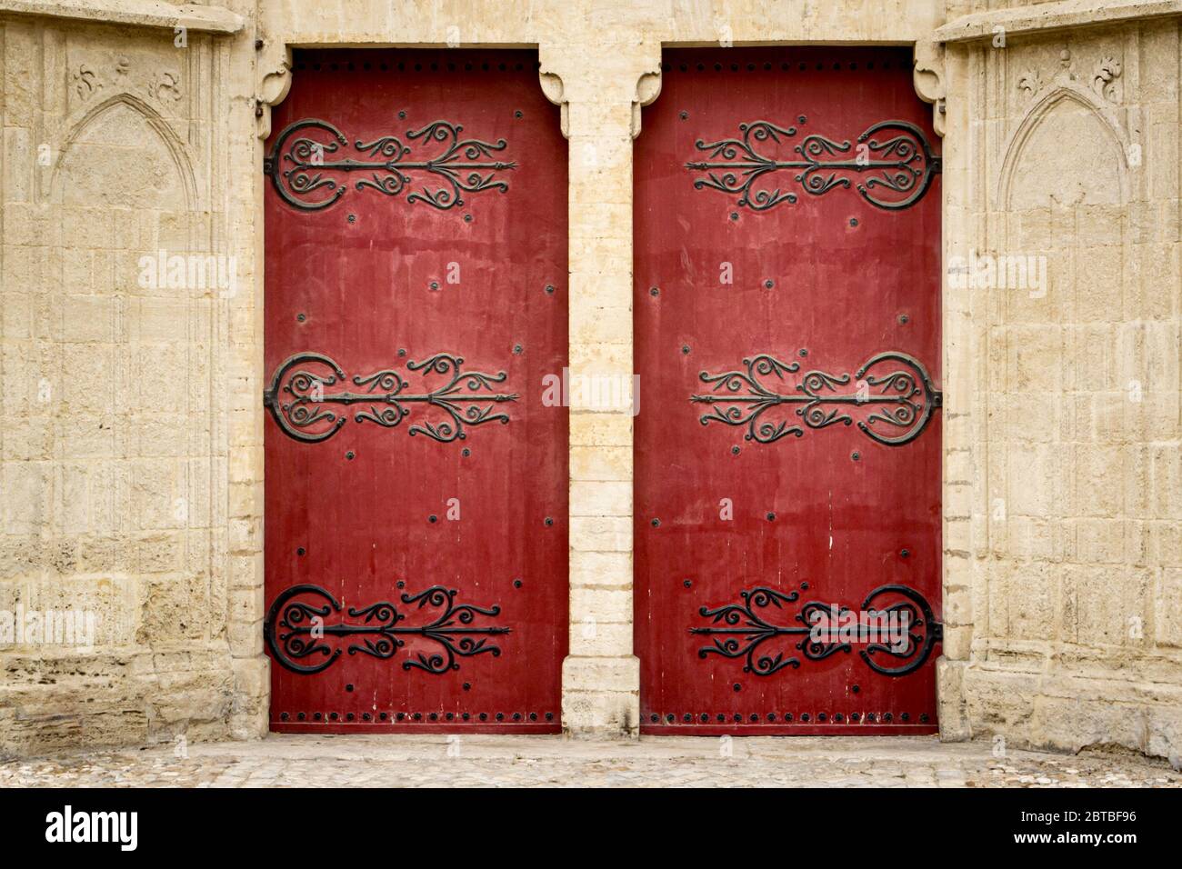 Verschlungene rote Holztüren an der Cathédrale Saint-Pierre in Montpellier, Frankreich. Stockfoto