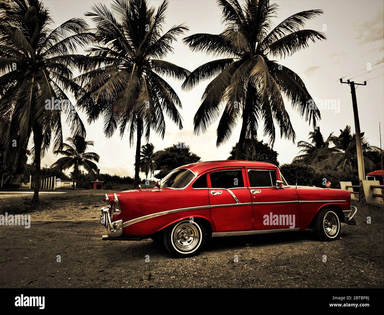 Alte rote klassische kubanische Auto und einige Palmen in karibischen Strand Umgebung Stockfoto