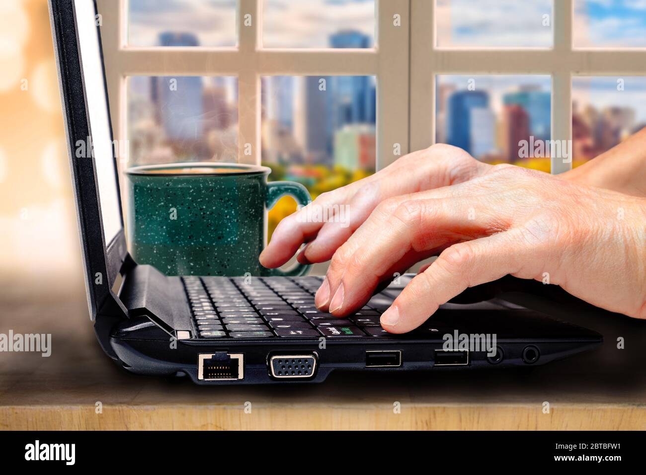 Nahaufnahme des Arbeitskonzepts von zu Hause aus in der neuen Normalität nach Covid-19 mit Fingern auf Computer-Laptop-Tastatur und Kaffee auf dem Tisch mit Vintage li Stockfoto