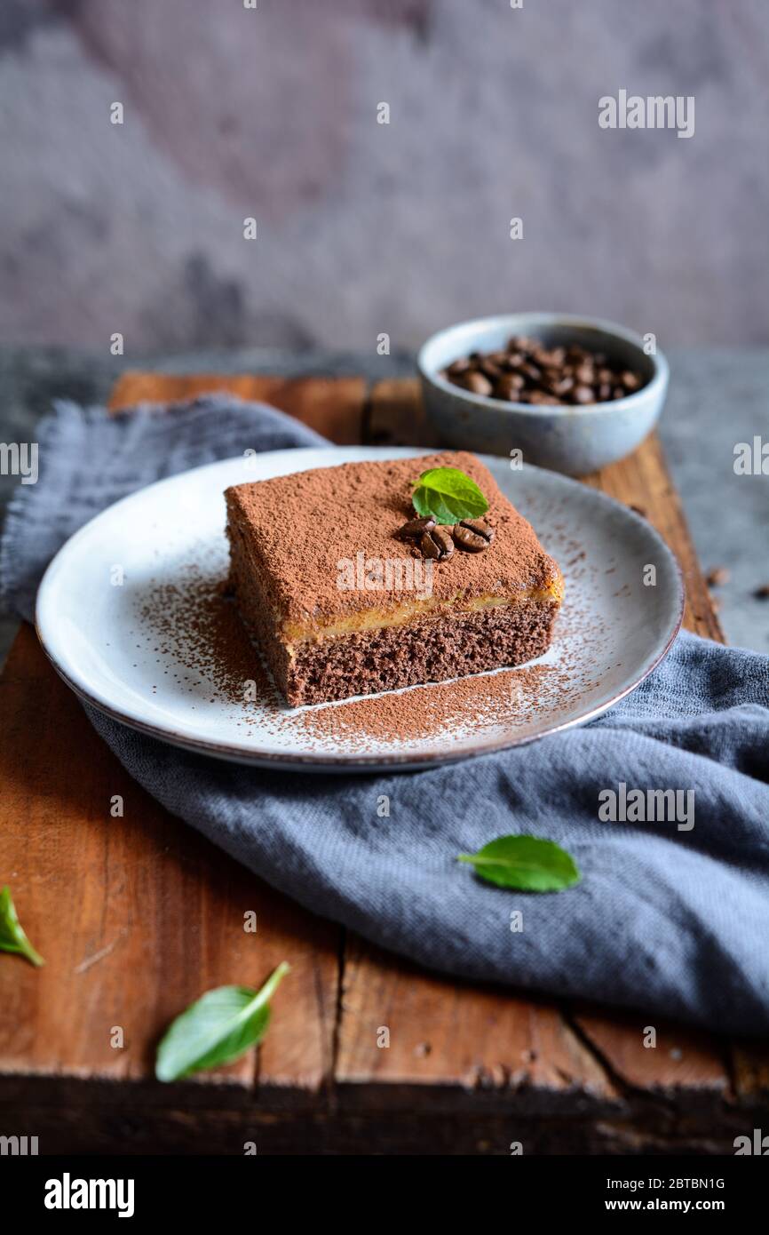 Dessert aus dunkler Schokolade mit Kaffeesahne und mit Kakaopulver auf einer Keramikplatte bestreut Stockfoto